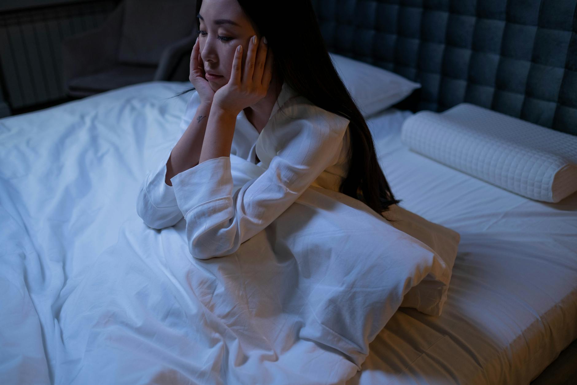 woman in white long sleeve shirt sitting on a bed